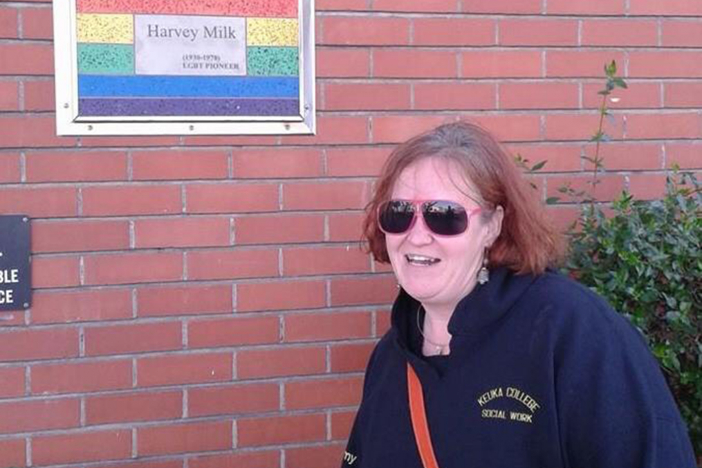 Amy Hickey poses alongside a plaque commemorating LGBTQ pioneer Harvey Milk